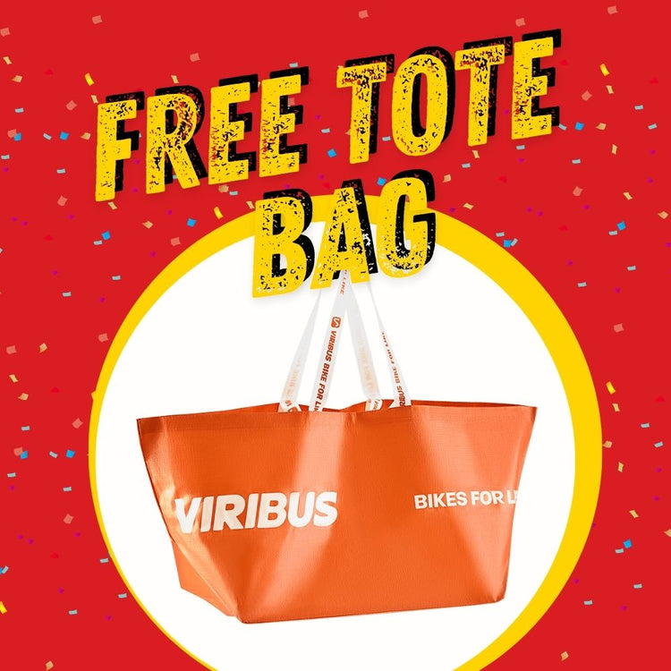 An image featuring a red and yellow circular label with the text 'FREE TOTE BAG' and a white bicycle-themed logo 'Viribus Bikes for Lives'. The background is celebratory with confetti and streamers.