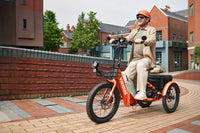 a man riding a fat tire electric tricycle on an urban road