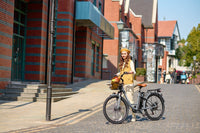 A woman riding a step-through electric bike on a road in an urban area