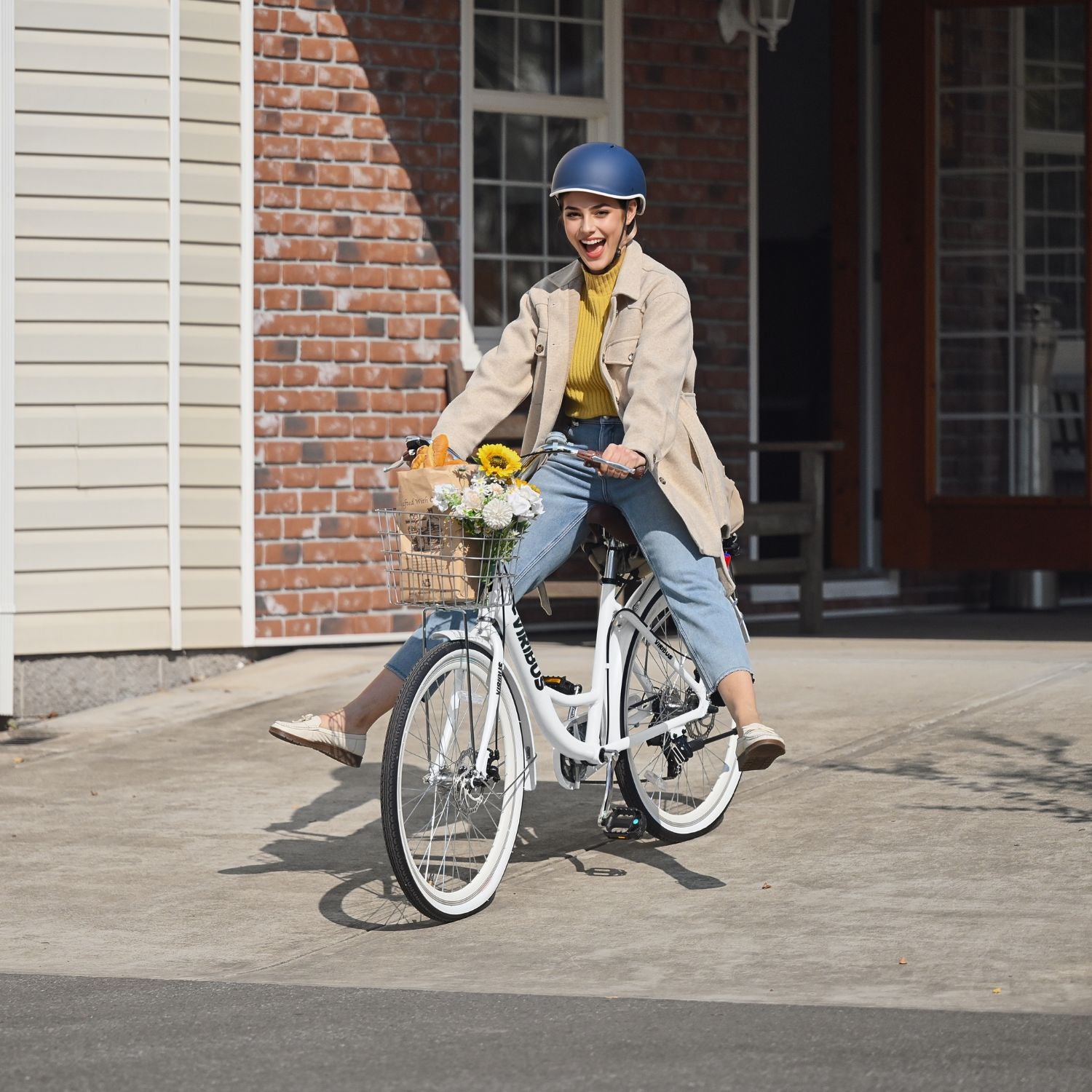 Woman riding a bicycle with a basket full of flowers on a sunny day.